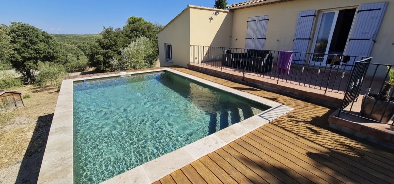 Conception et construction de piscine avec margelle travertin attenant à une maison neuve à Nîmes dans le 30